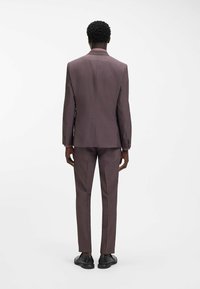 Herren-Zweiteiler in dunklem Pflaumenton, mit maßgeschneiderter Passform, einreihigem Schlitz am Sakko und gerade geschnittenen Hosen. Glatter Stoff.