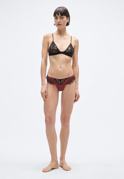Μαύρο δαντελένιο σουτιέν bralette με λεπτές τιράντες και κυματιστά άκρα, συνδυασμένο με μπορντό εσώρουχο με δαντελένιο τελείωμα και κολακευτική γραμμή.