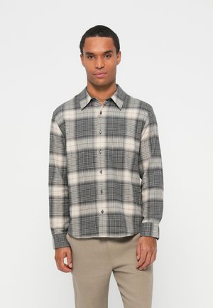 Plaid shirt featuring black, white, and gray hues, made of woven fabric, long sleeves, and a button-down front with a smooth texture.