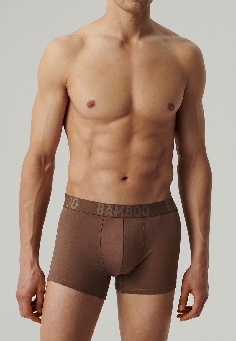 Bambusowe bokserki w ciemnym brązie, charakteryzujące się miękką fakturą i elastycznym paskiem, na którym w kontrastowym kolorze widnieje napis "BAMBOO".