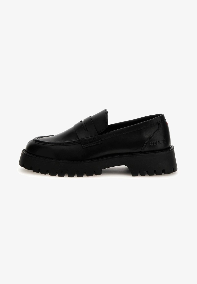 Mocassin en cuir noir à semelle épaisse, design classique avec bride penny et logo embossé "GUESS" sur le côté du talon.