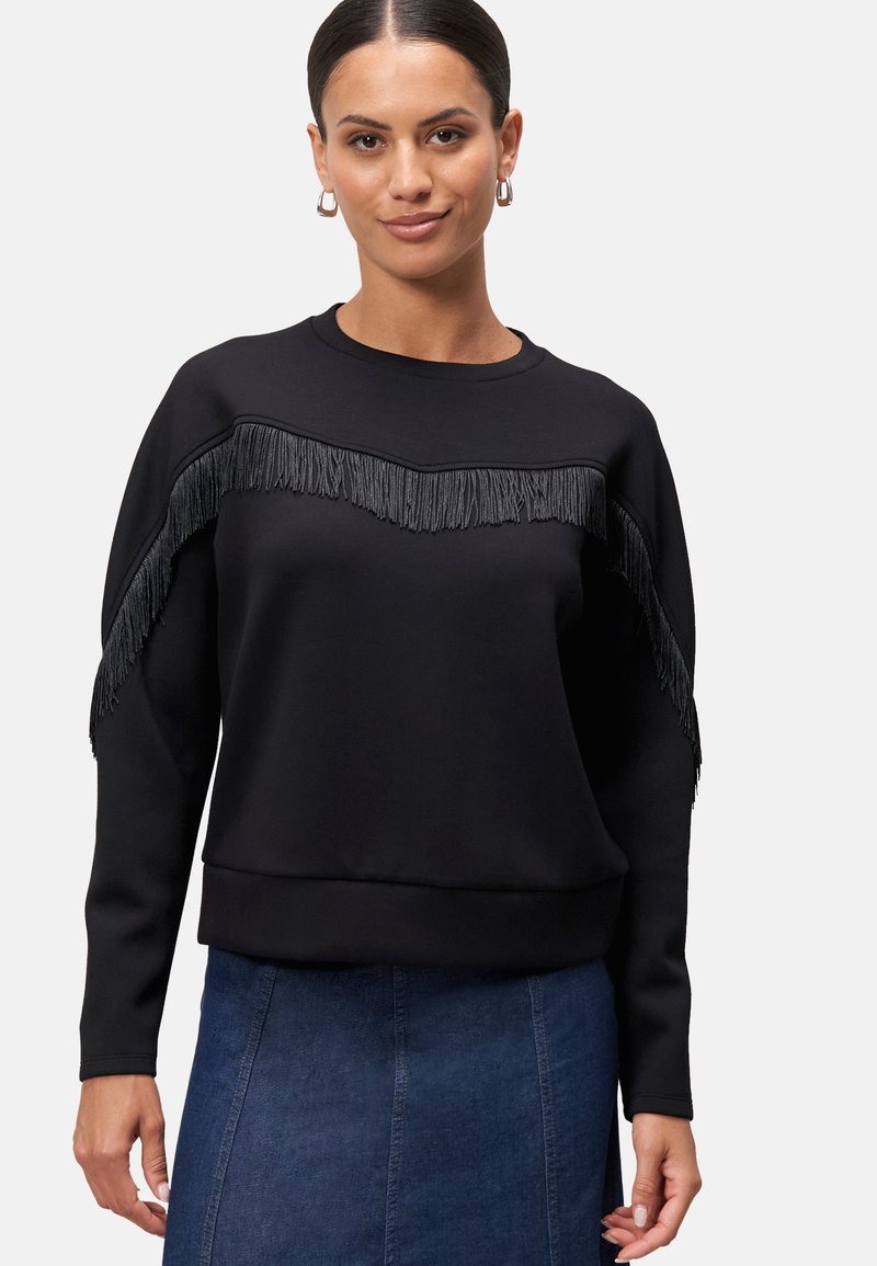 Černá mikina se třásněmi na hrudi, kulatým výstřihem a dlouhými rukávy. Hladká textura, volný střih.