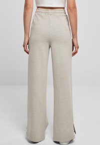 Wijdvallende beige sweatpants met een elastische tailleband, gemaakt van zachte stof, met zijsplitten aan de zoom voor extra detail.