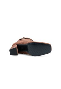 Stivale alla caviglia in suede marrone con tacco a blocco, caratterizzato da una tomaia liscia e una suola in gomma nera testurizzata con un design del battistrada a motivo.