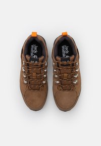 Braune Wildlederschuhe für Wanderungen verfügen über Metallösen, orange Schnürsenkel und ein schwarzes Logo auf der Innensohle. Das Design umfasst einen gepolsterten Schaft und eine Zehenkappe.
