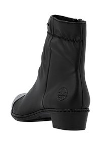 Bota de cuero negra hasta mitad de la pantorrilla con tacón bajo, suela cosida y logo circular en relieve en el lado exterior.