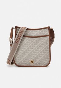 Geantă crossbody bej cu material textil cu model și logo-ul 'MK', accente din piele maro și o curea ajustabilă cu detalii cu logo. Accesorii metalice aurii.