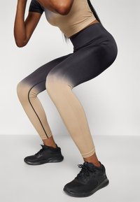 Legíny s vysokým pasem s ombré designem, který přechází od béžové po tmavě šedou, vyrobené z elastického materiálu s hladkou texturou.