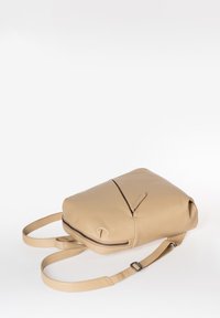 Beige leren rugzak met een ronde vorm, enkele ritszak, verstelbare bandjes en een gladde textuur. Minimalistisch ontwerp met subtiele accenten.