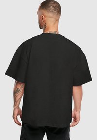 Sort oversized t-shirt med en afslappet pasform, korte ærmer og rund hals. Har en glat stof og en lige kant.