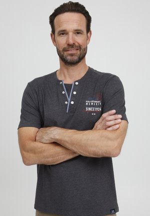 Pilkos spalvos trumpo rankovio marškinėliai iš medvilnės ir poliesterio mišinio su mygtukais Henley apykakle, dekoruoti siuvinėjimais ir kontrastinėmis siūlėmis ant pečių.