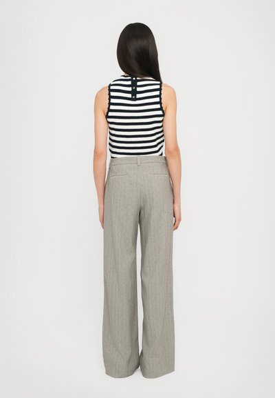 Top tanpa lengan rajut bergaris dalam warna navy dan putih, dipadukan dengan celana panjang garis-garis abu-abu dengan desain lebar dan saku belakang.
