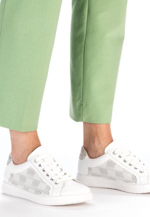 Witte sportieve schoenen met geperforeerd ontwerp en zilveren accenten, gecombineerd met groene cropped broek. Gladde textuur, low-profile silhouet.
