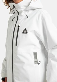 Witte waterdichte jas met hoge kraag, verstelbare capuchon, zijzak met rits en een textuur accent aan de zijkant met een logopatch.