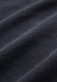 Dunkelblauem Stoff mit glatter Textur, der mehrere sanfte Falten und einen subtilen Glanz zeigt, was auf eine Mischung aus Komfort und Haltbarkeit hinweist.