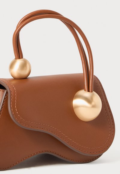 Ruskea nahkainen laukku, jossa on kaareva läppä, kaksi pyöreää kahvaa ja suuria kultaisia pallomaisia koristeita, jotka kiinnittävät kahvat laukkuun.