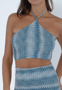 Top corto halter zigzag blu e grigio realizzato in tessuto leggero, con scollatura incrociata e design aderente.