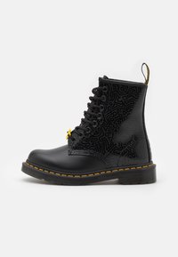 Botas de tobillo negro con cordones, diseño estampado, ojales amarillos y costuras amarillas, con punta redonda y suela de goma resistente.