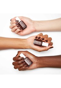 Bouteilles de vernis à ongles Essie tenues dans trois mains. Chaque main montre des tons de peau différents avec du vernis à ongles brun foncé et une finition brillante.
