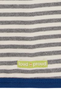 Top in tessuto a righe di colore bianco sporco e grigio, con un orlo blu e un'etichetta verde con la scritta "loud + proud" in basso.