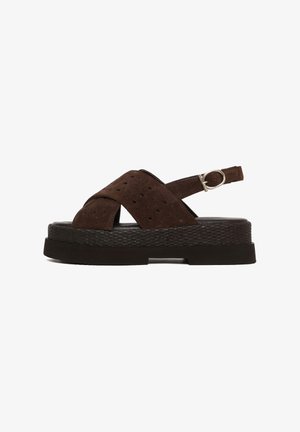Dark brown suede platform sandal with perforated crisscross straps, adjustable ankle strap, and textured sole.