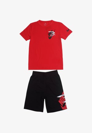 Maglietta rossa a maniche corte con logo Nike nero sul petto; abbinata a pantaloncini neri con un grande logo Nike rosso sul lato. Tessuto in cotone.