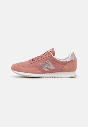 Růžová teniska New Balance s kombinací semiše a textilu, bílou polstrovanou podrážkou, šněrováním a výrazným logem "N" na boku.