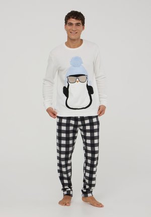 Maglione bianco a maniche lunghe con design di un pinguino che indossa occhiali e un cappello blu. Pantaloni da pigiama in pile a scacchi bianchi e neri.