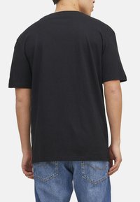 Sort bomulds T-shirt med en afslappet pasform, korte ærmer og rund halsudskæring, parret med blå denim jeans med baglommer.