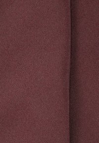 Tessuto bordeaux con una trama liscia e motivo a trama diagonale. Il materiale sembra spesso e resistente, adatto a varie applicazioni.
