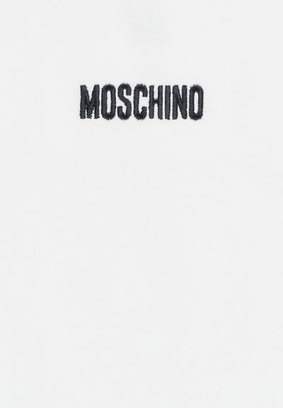 T-shirt bianco con "MOSCHINO" ricamato in nero, che presenta un design semplice e pulito senza ulteriori motivi o accenti.