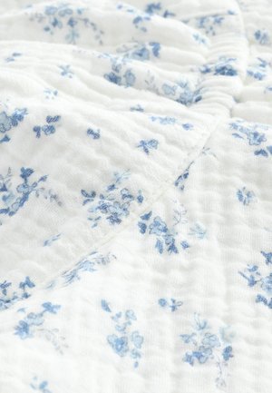 Hvidt stof med en tekstureret, krøllet overflade, prydet med et delikat blåt blomsterprint spredt over det.