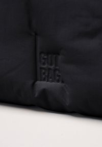 Borsa in tessuto nero con il logo "GOT BAG" in rilievo. Texture liscia, forma rettangolare, design minimalista, adatta all'uso quotidiano.