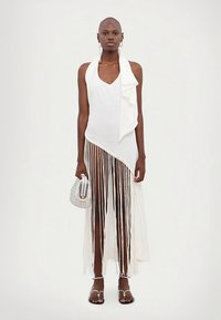 Balta asimetrinė suknelė su kutais, minkšta medžiaga ir raukiniais. Derinama su sidabriniais aksesuarais ir minimalistinėmis basutėmis.