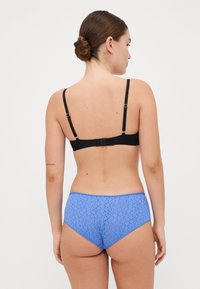 Soutien-gorge noir avec bretelles réglables assorti à une culotte bleue taille haute présentant un délicat motif texturé. Vue de dos.