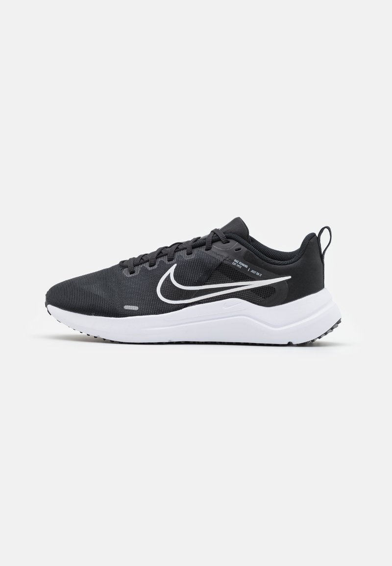 Chaussure de sport noire avec une tige en mesh, logo swoosh blanc, design à lacets, et une semelle blanche amortissante avec une adhérence texturée.