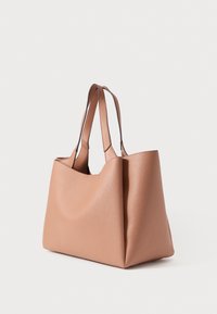 Strukturált táska világosbarna, texturált bőrből. Két masszív fogantyúval és széles nyílással rendelkezik, mely sima, ívelt sziluettet alkot.