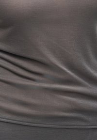 Κοντινή λήψη ρυτιδιασμένου σκούρου γκρι υφάσματος με ρίγες, που δείχνει υφή και οριζόντιες πτυχές.