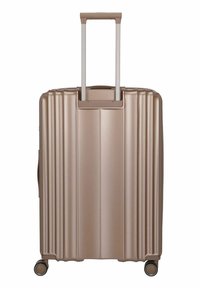 Valise rigide en or rose métallique, avec des rainures verticales, une poignée rétractable et quatre roues pour une maniabilité aisée.