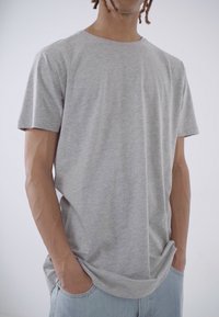 Tricou din bumbac gri cu mâneci scurte și decolteu rotund. Textură netedă și croială lejeră, asortat cu blugi din denim deschis.