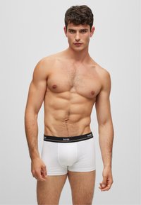 Boxers ajustados de algodón blanco con una cinturilla elástica negra que presenta el logo "BOSS" en blanco. Textura suave, diseño ajustado y longitud a mitad del muslo.