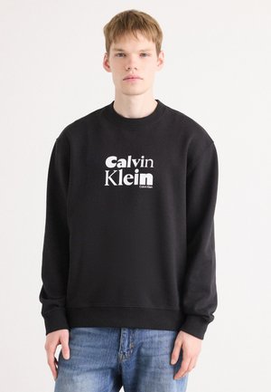 Zwarte sweatshirt van zachte stof. Heeft een ronde hals en ribgebreide manchetten. Voorzijde toont een groot wit 'Calvin Klein' logo. Casual pasvorm.