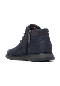 Botas de tobillo de piel azul marino con cremallera lateral, parte superior texturizada, cuello acolchado y forro de cuadros. Suela de goma flexible para mayor comodidad.