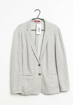 Lysegrå langærmet blazer med to knapper og forlommer, hængende på en sort bøjle med en hvid stregkode-tag fastgjort.