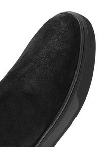 Czarne zamszowe buty o gładkiej powierzchni, zaokrąglonym nosie i teksturowanym wykończeniu. Gumowa podeszwa z niewielkim bieżnikiem i minimalistycznym designem.