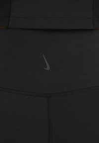 Czarne legginsy Nike z gładkiego, elastycznego materiału. Posiadają małe czarne logo w okolicach pasa oraz detale szwów płaskich.