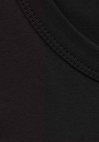 Tela de algodón negra con una textura suave y un escote acanalado. Dos tonos de negro crean un contraste sutil en el material.