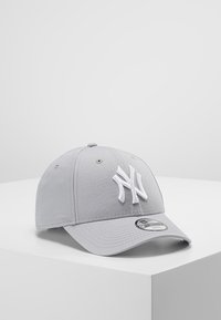 Szürke vászon baseballsapka, kiemelkedő fehér hímzett "NY" logóval az elején, hajlított sárral és állítható hátlappal.