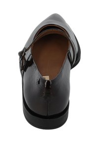 Scarpa in vernice nera con punta affilata e una singola fascia sulla parte superiore. Suola piatta e semplice fodera interna marrone.