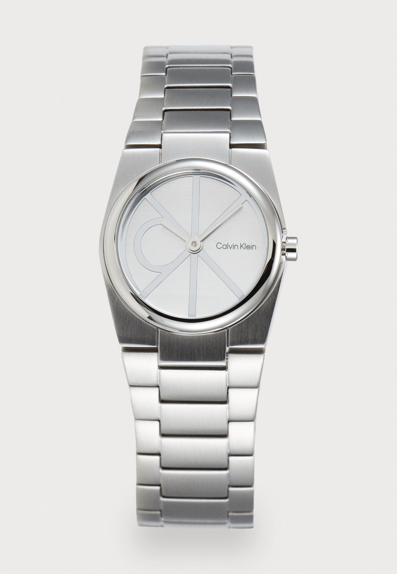 Zilveren roestvrijstalen horloge met een ronde wijzerplaat, minimalistisch ontwerp en een grijze wijzerplaat met de merknaam en cirkelvormige patronen.